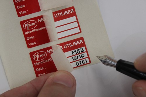 Handwritten label being filled out with ink pen